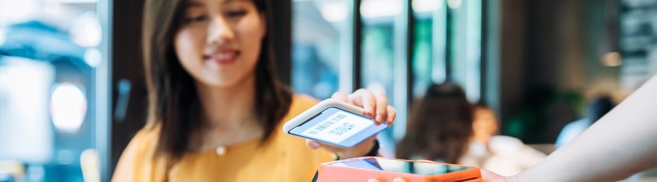 Young Asian-American woman using contactless payment with smartphone