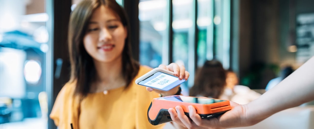 Young Asian-American woman using contactless payment with smartphone
