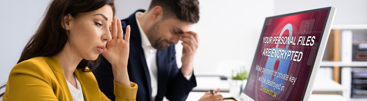 Frustrated business owners looking at computer screen with ransomware message
