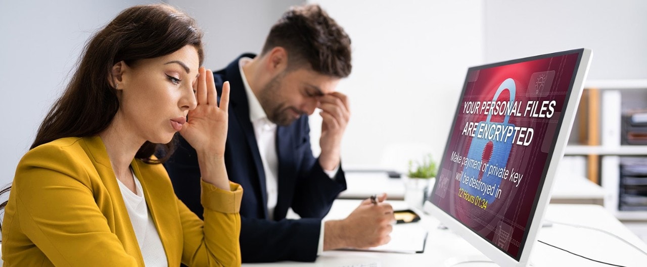 Frustrated business owners looking at computer screen with ransomware message