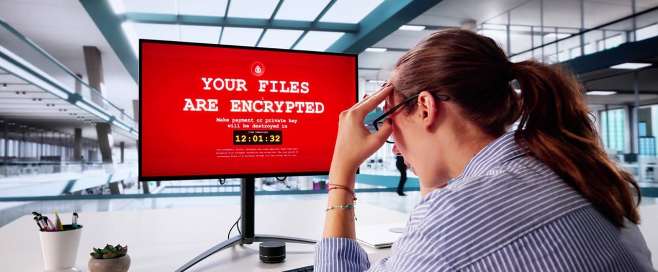 Stressed out businesswoman looking at her computer which has been infected with ransomware