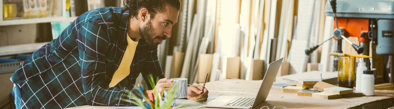 Lumber company business owner leaning on desk looking at laptop