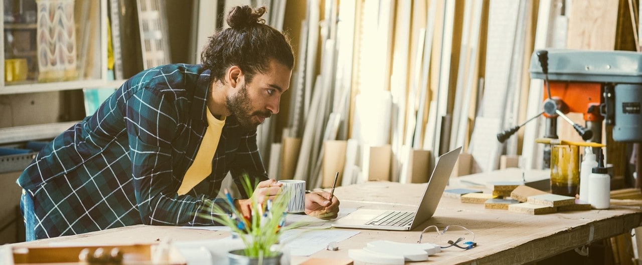 Lumber company business owner leaning on desk looking at laptop