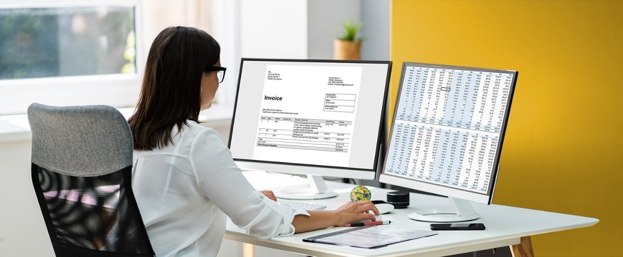 Female business owner reviewing finances on two computer screens