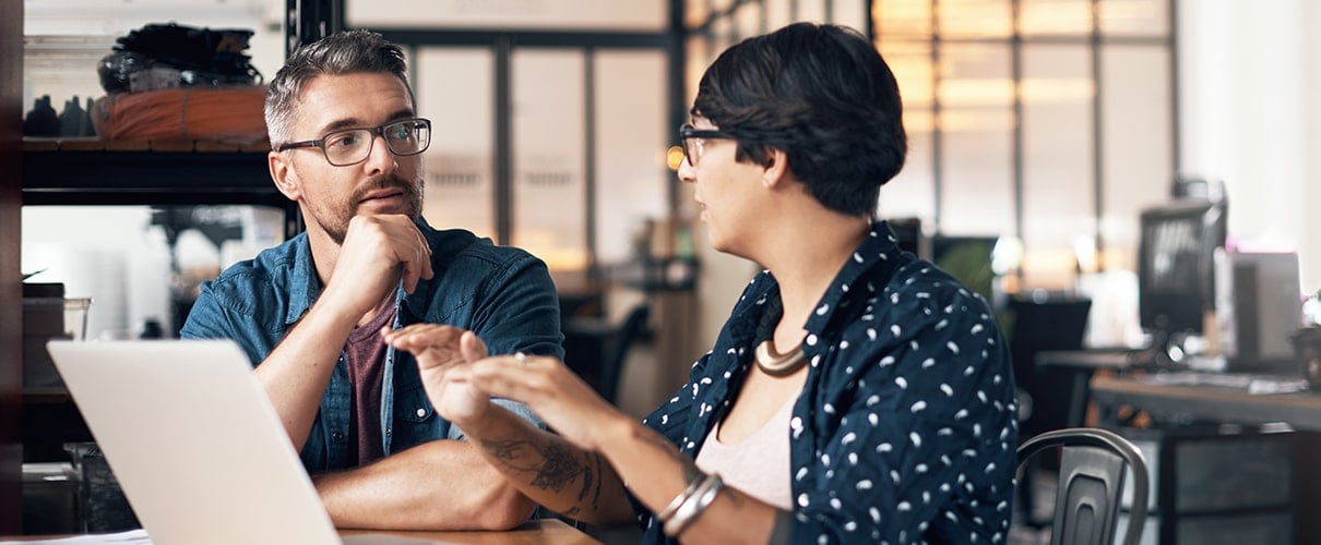 man and woman using a laptop while working on a project together in a workshop