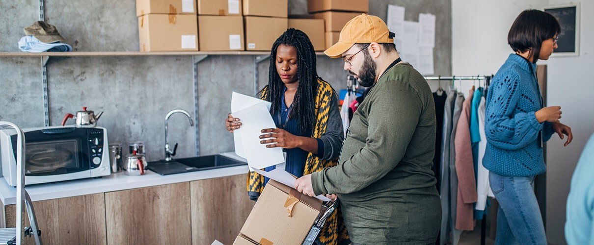 Multi-ethnic group of men and women arranging customer orders for drop shipping in warehouse.