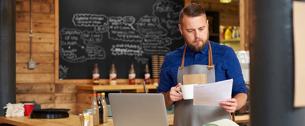 coffee shop owner checks the delivery notes in his bookkeeping folder