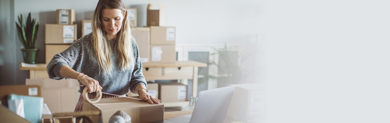 Working woman at online shop packaging goods for delivery