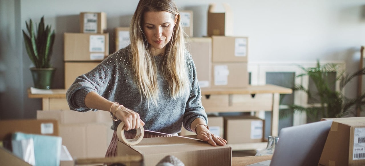 Working woman at online shop packaging goods for delivery