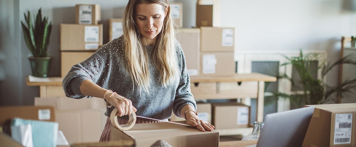 Working woman at online shop packaging goods for delivery