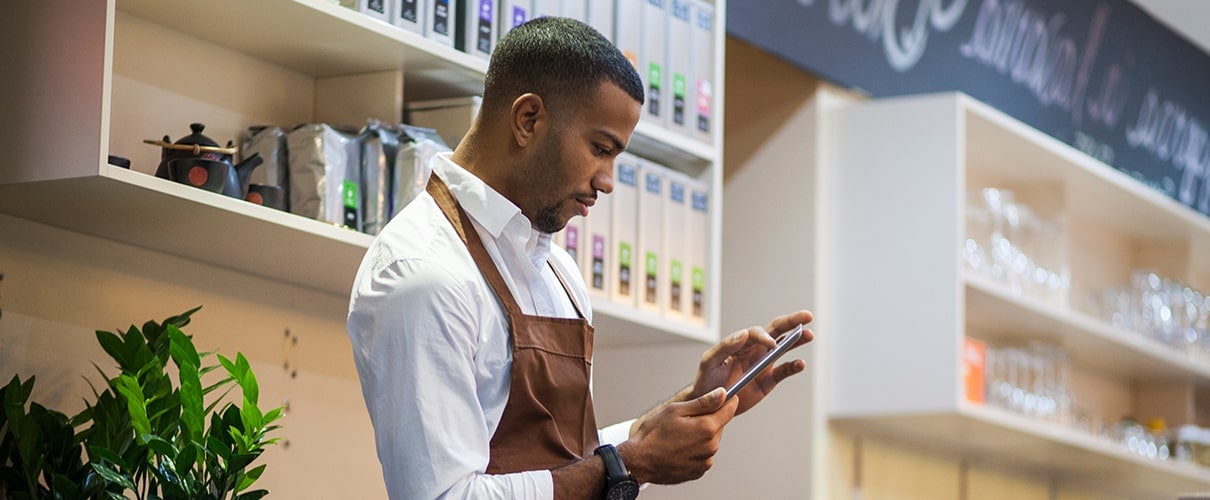 African-American business owner using smartphone in his coffee shop