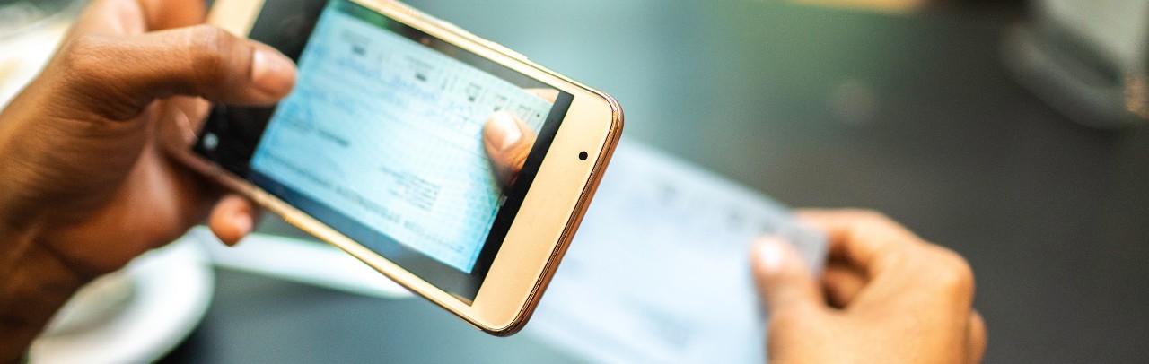 Young woman depositing check by phone in the cafe