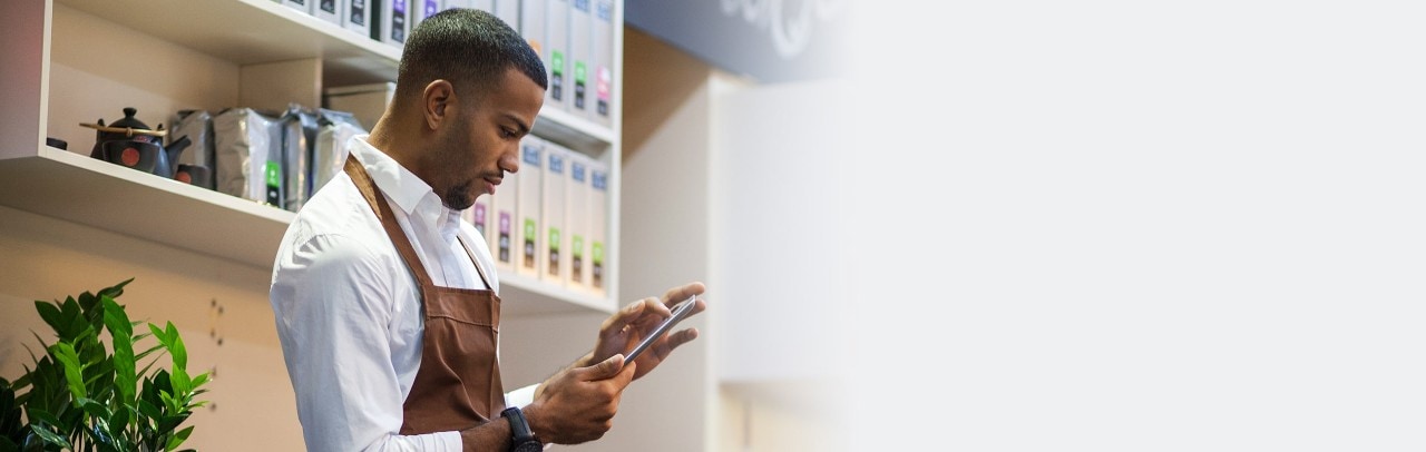 African-American business owner using smartphone in his coffee shop