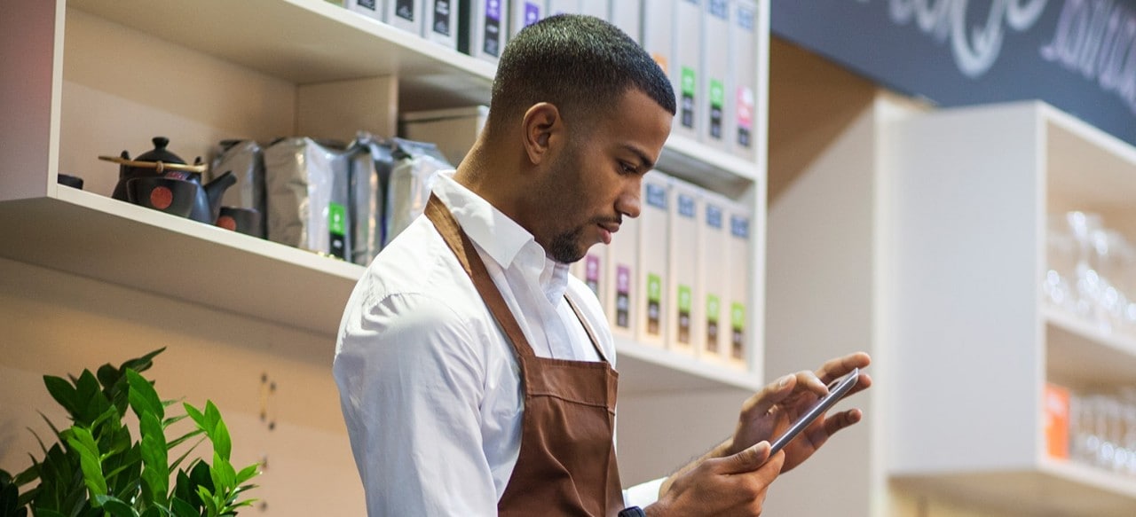 African-American business owner using smartphone in his coffee shop