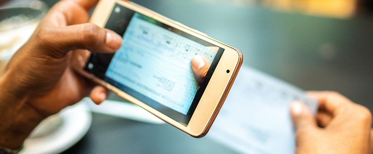 Young woman depositing check by phone in the cafe