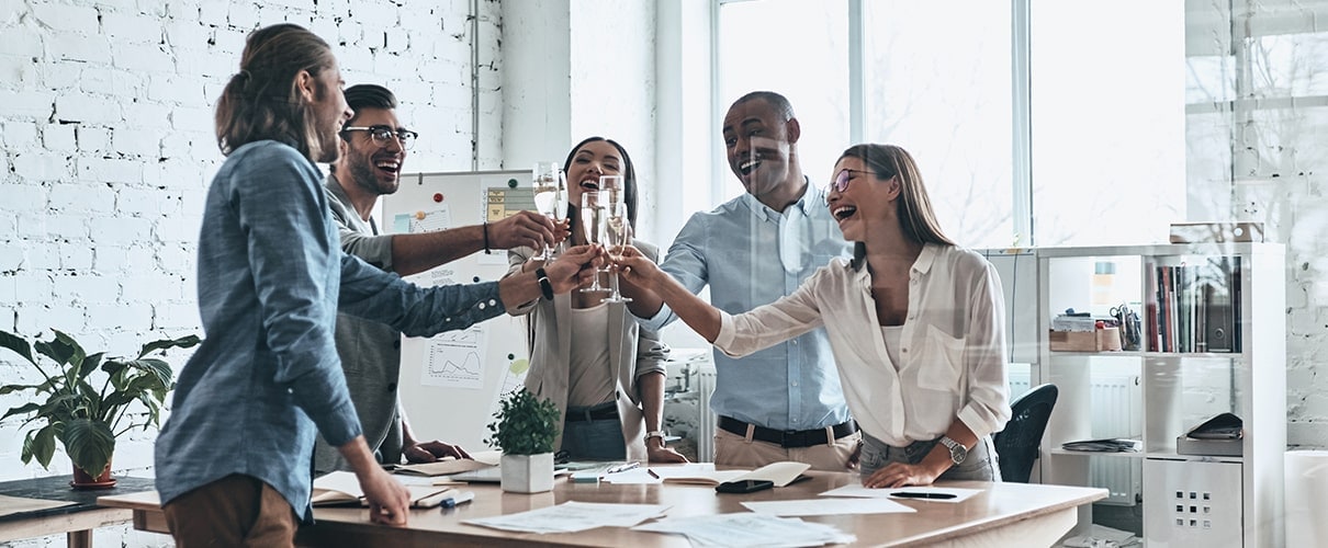 Group of happy business people toasting each other and smiling while standing in the board room