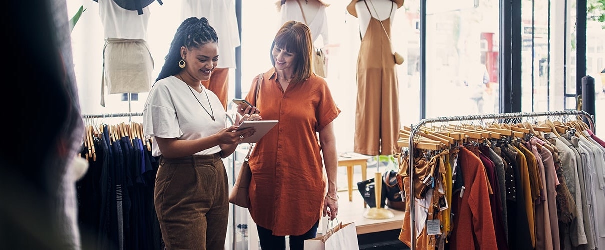 Shot of a shop assistant using a digital tablet while assisting a customer in a boutique