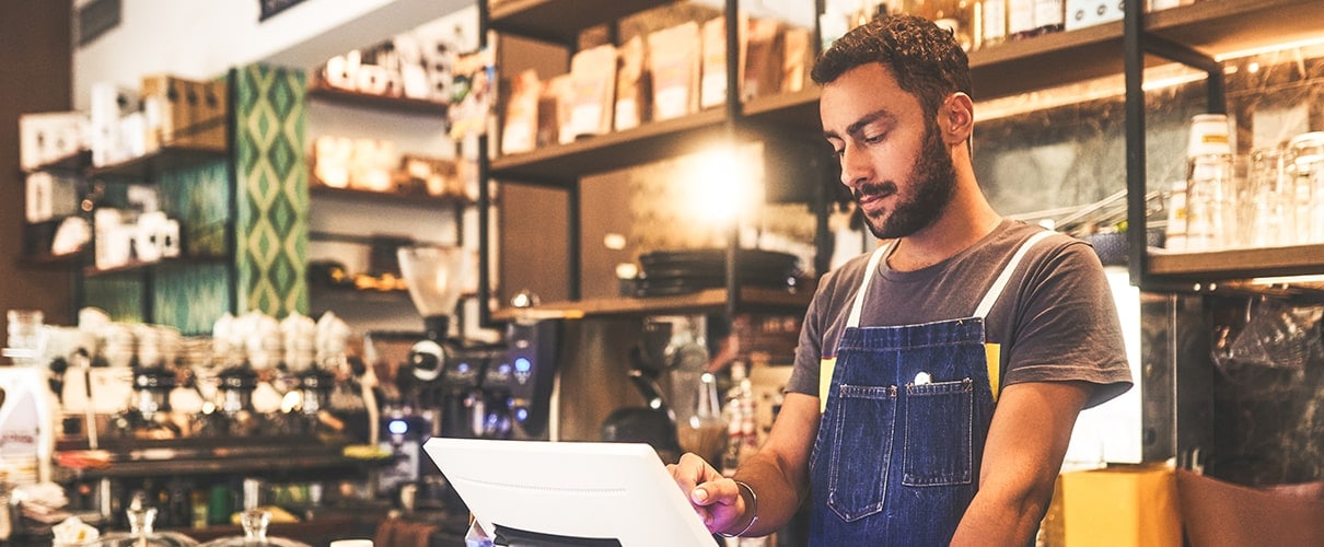 young man using a till in a cafe