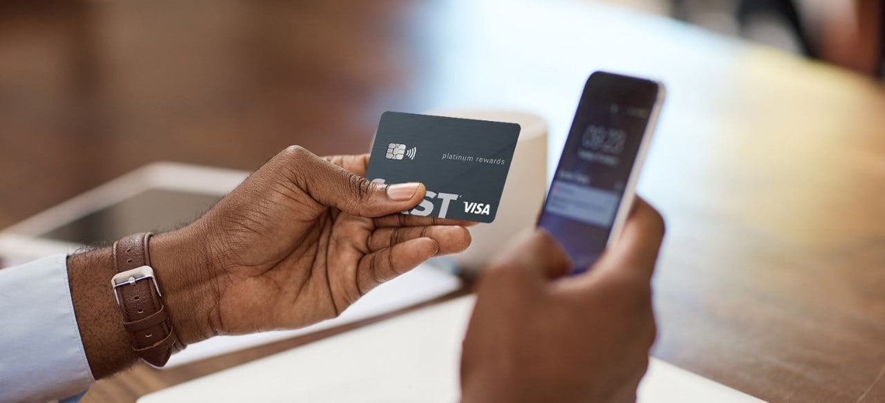 African-American man holding a First Financial Visa Platinum Rewards Credit Card and a smartphone