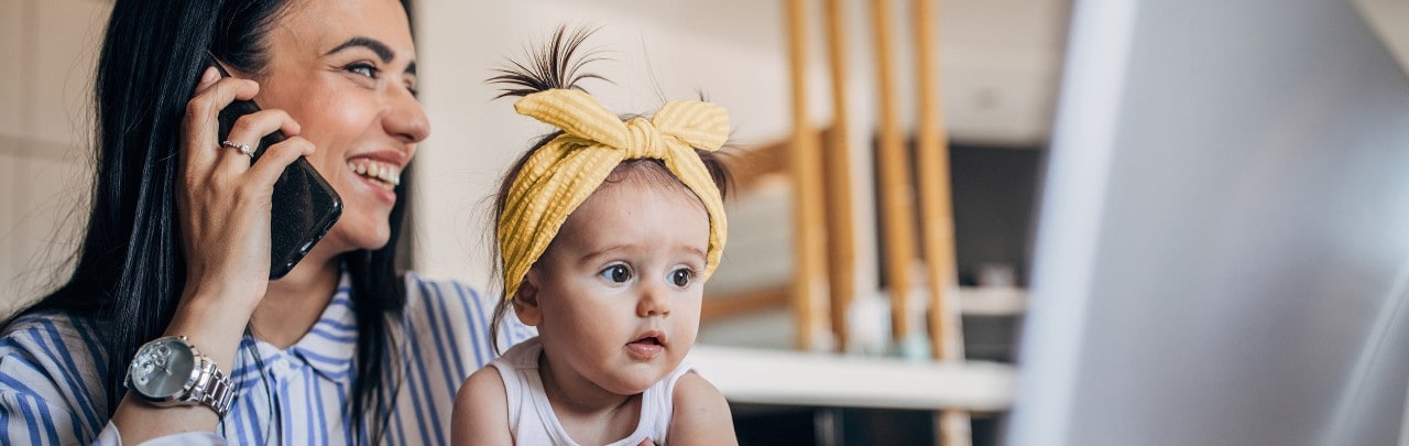 Mother on phone call, holding baby daughter wearing yellow bandana