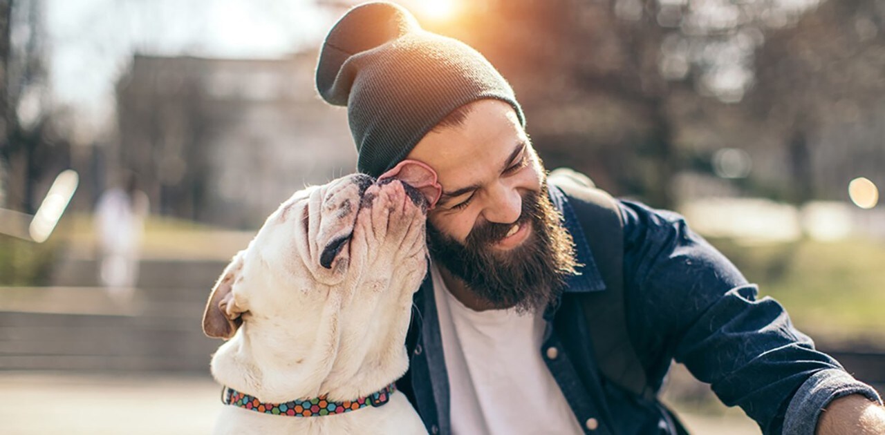 A dog licking its owner's smiling face