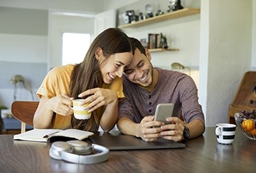 Couple sitting at table looking at smartphone