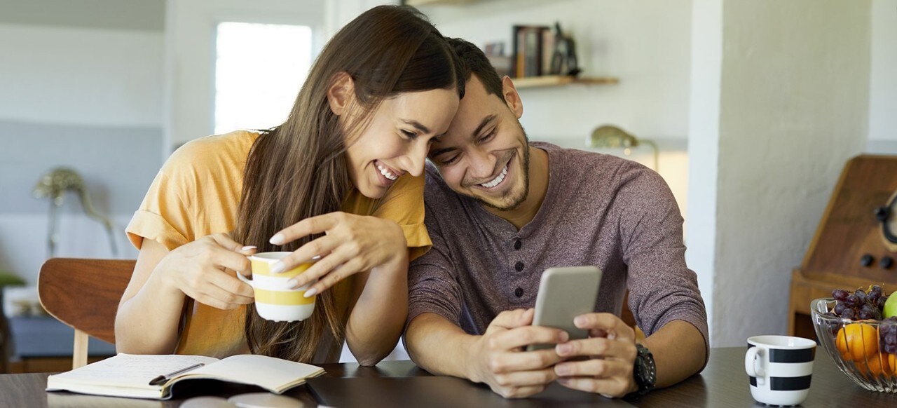 Couple sitting at table looking at smartphone