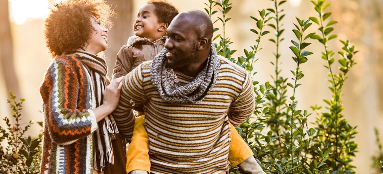 African-American family with father giving young daughter a piggy-back ride