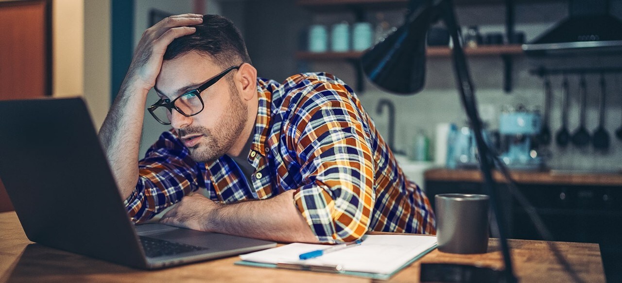 Frustrated man looking at computer with hand on his head