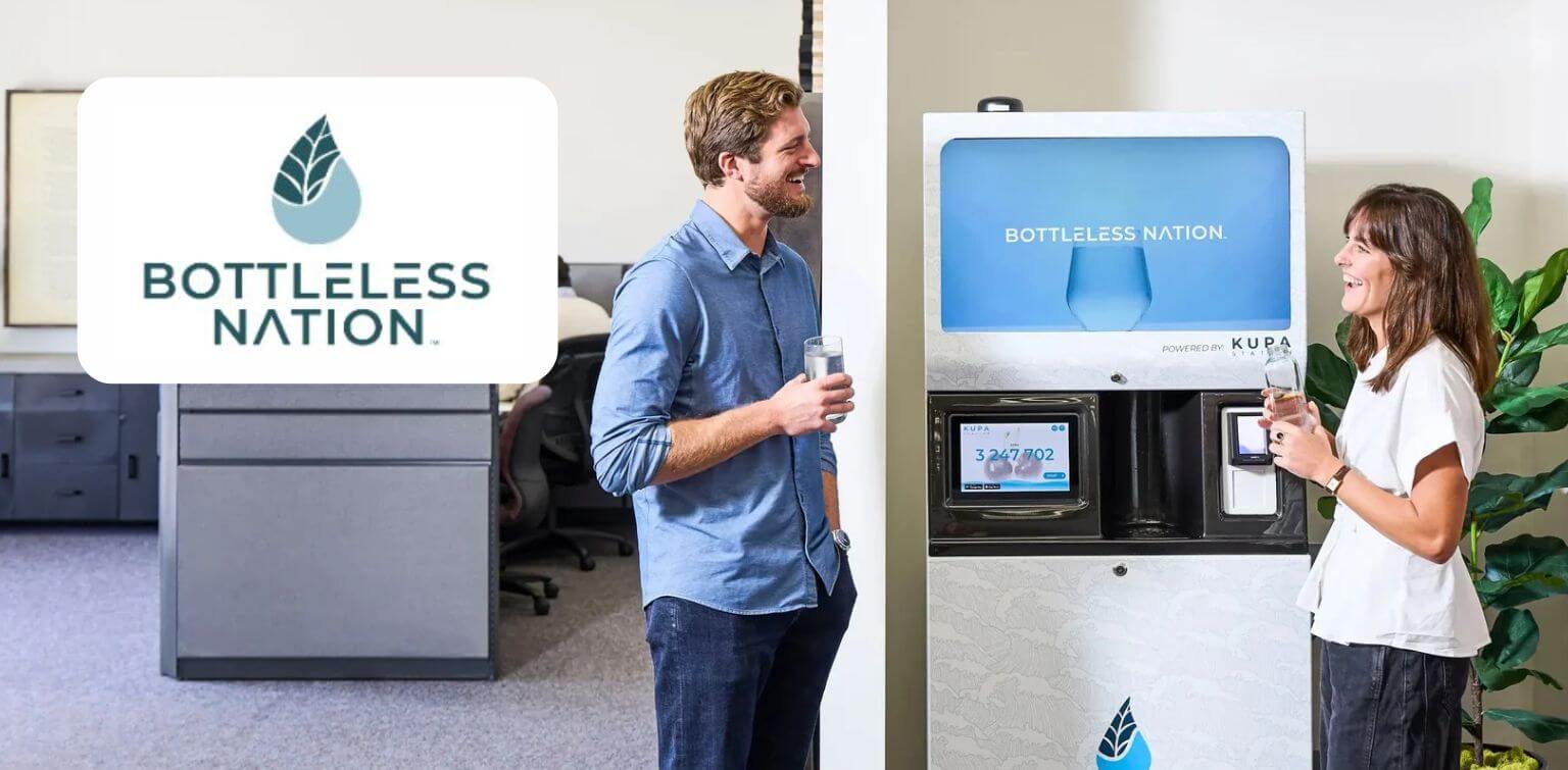 Two young workers in an office talking and smiling around a modern water dispenser, adjacent to superimposed Bottleless Nation logo