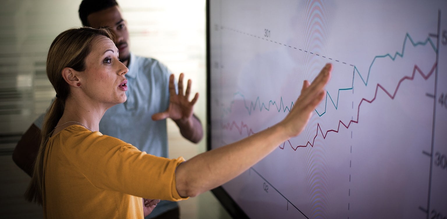 Female business owner showing employee profit tracking on large screen