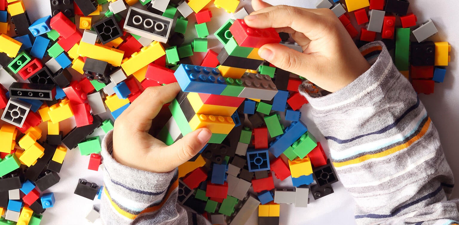 Close up of child's hand playing plastic toy building blocks