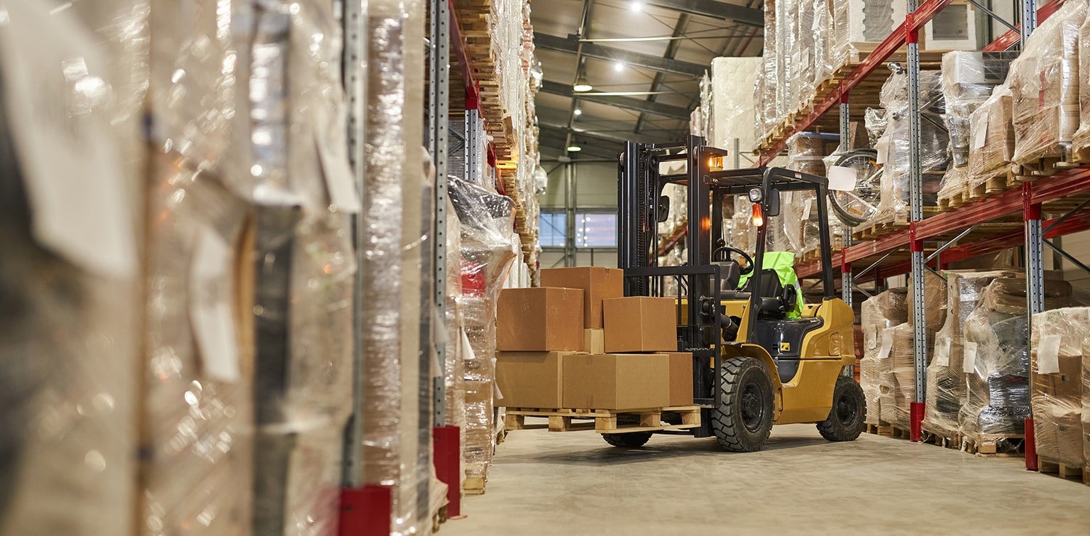 Forklift moving boxes in shipping warehouse
