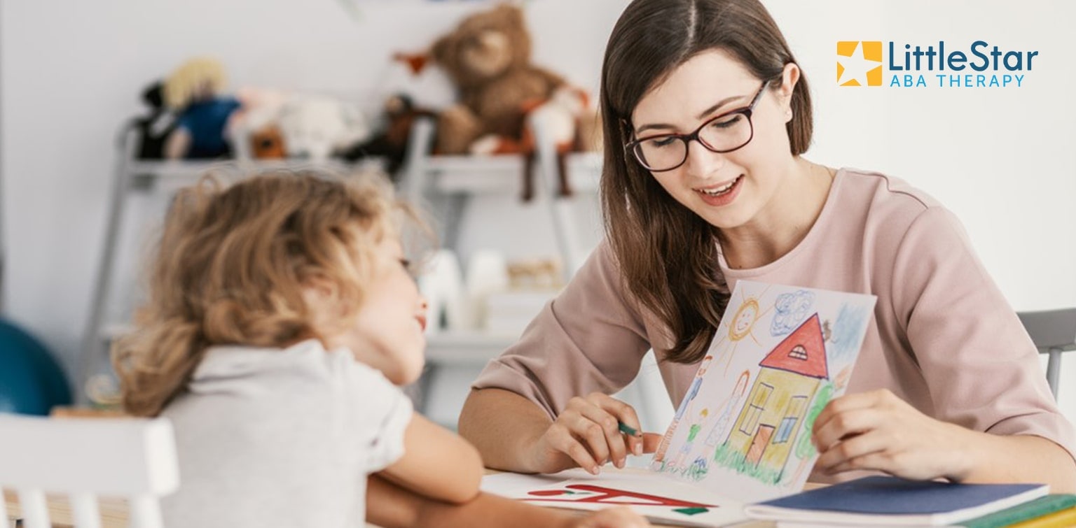 Woman and young girl looking at girl's drawing, with LittleStar ABA Therapy logo in corner