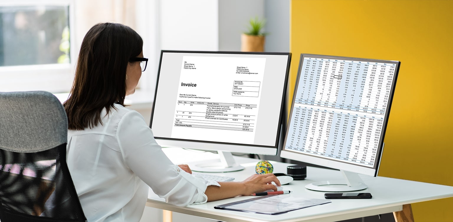 Female business owner reviewing finances on two computer screens