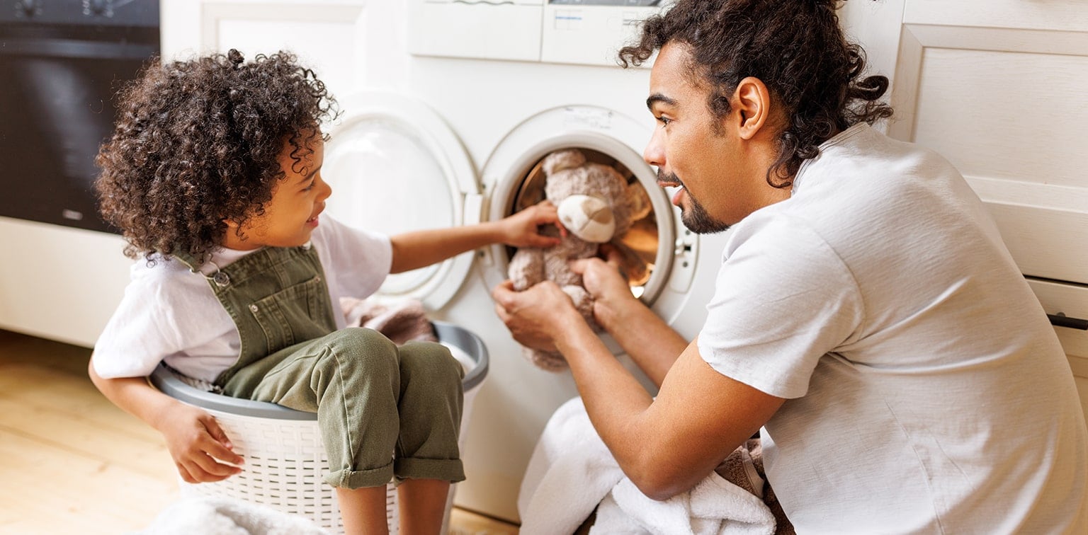 Father and young child doing laundry