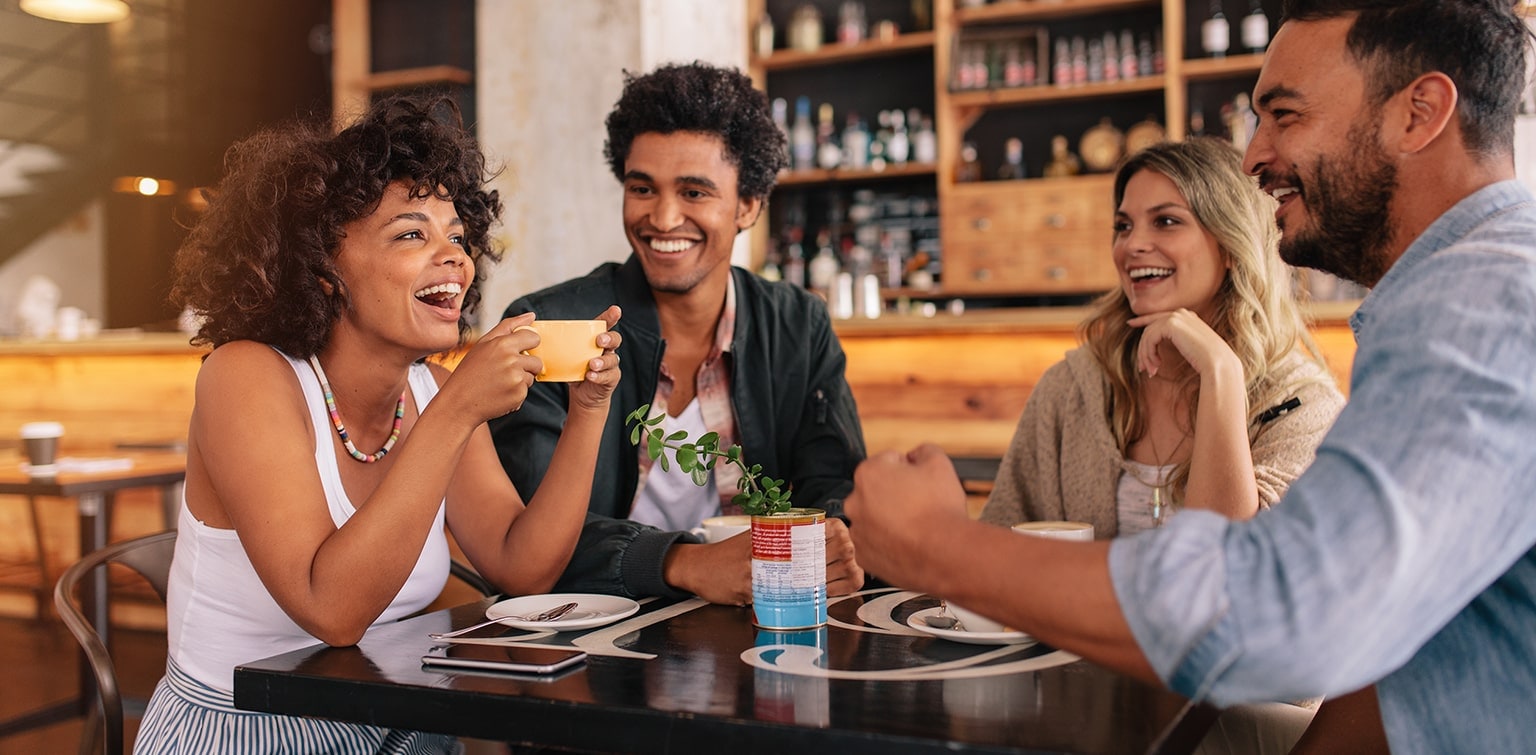 Diverse group of friends sitting at table in coffee bar
