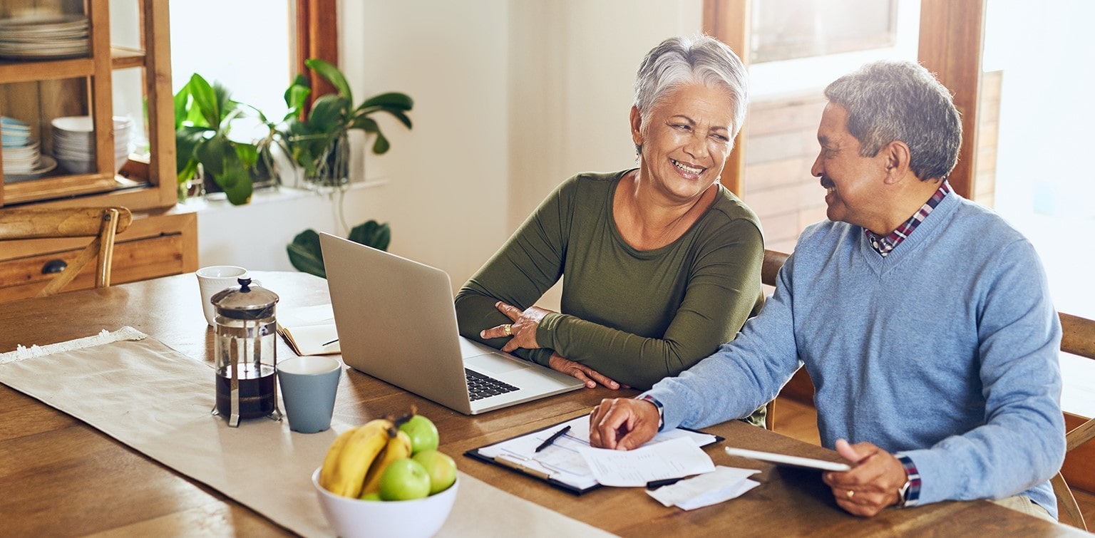 Smiling senior couple reviewing finances at a laptop