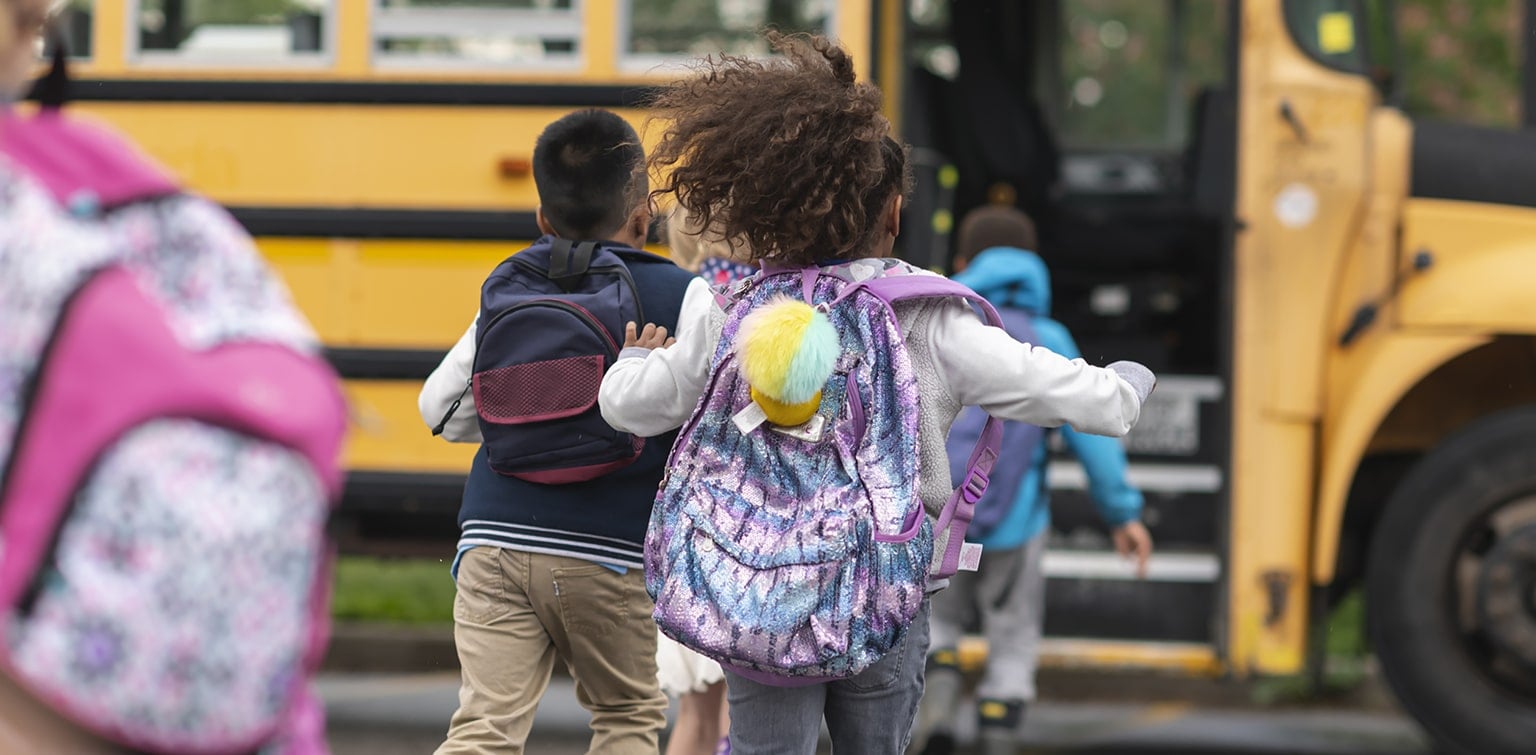 Group of children with backpacks running to school bus