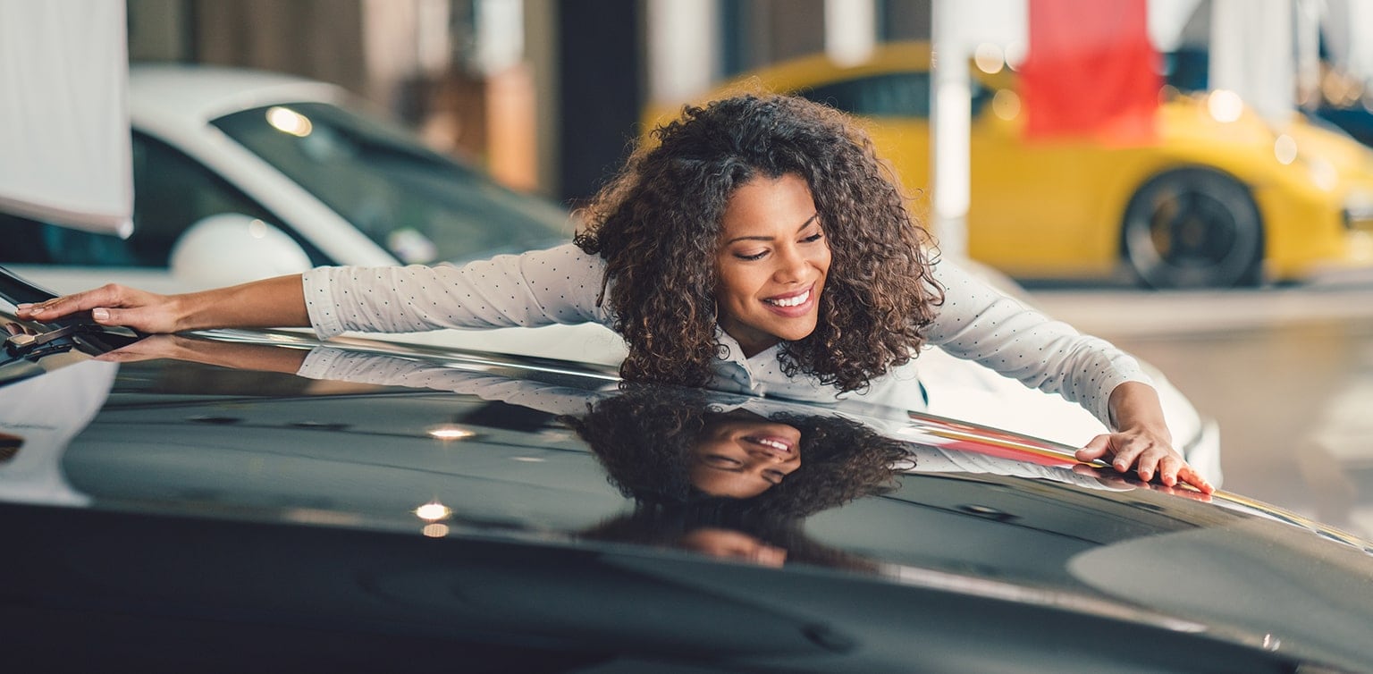 Woman admiring a luxury car in a dealership