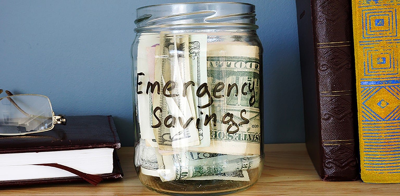 Jar on bookshelf with emergency savings cash