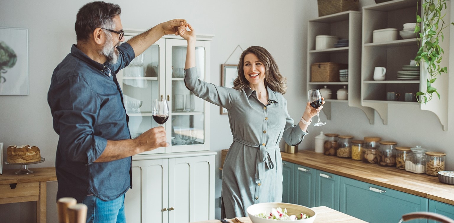 A retired couple dance together in the kitchen after finalizing their estate planning documents