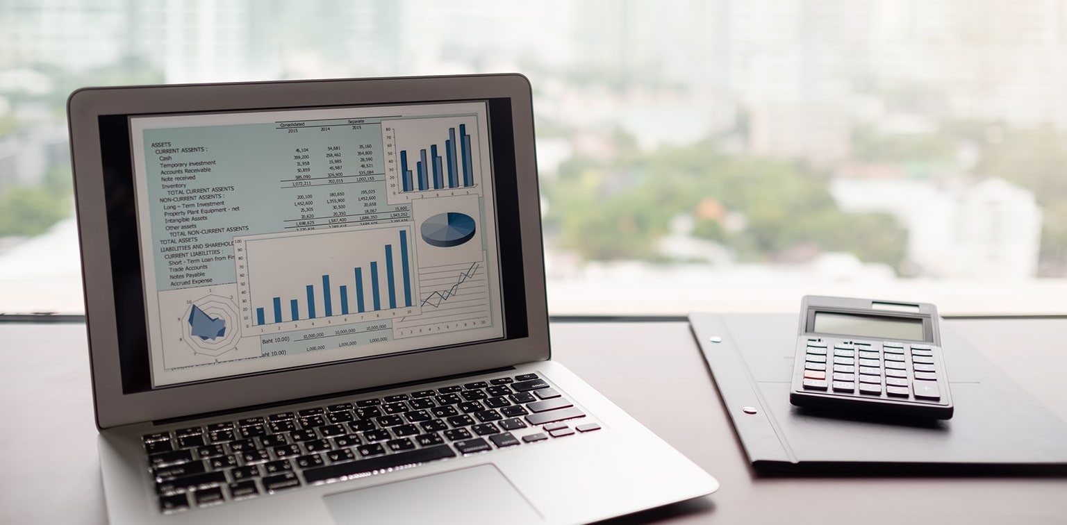 Open laptop displaying financial data, next to calculator