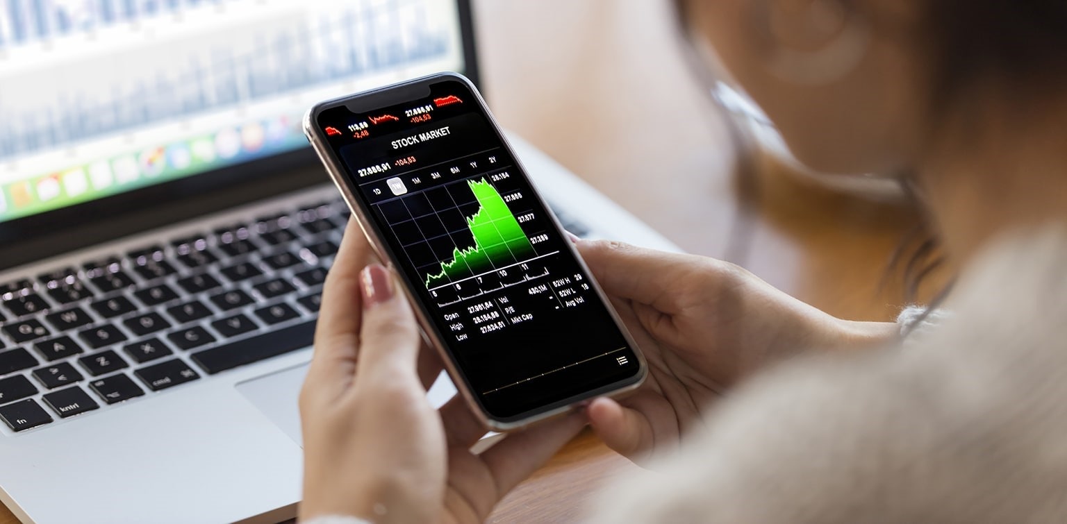 Young female finance professional reviewing stock data on a smartphone