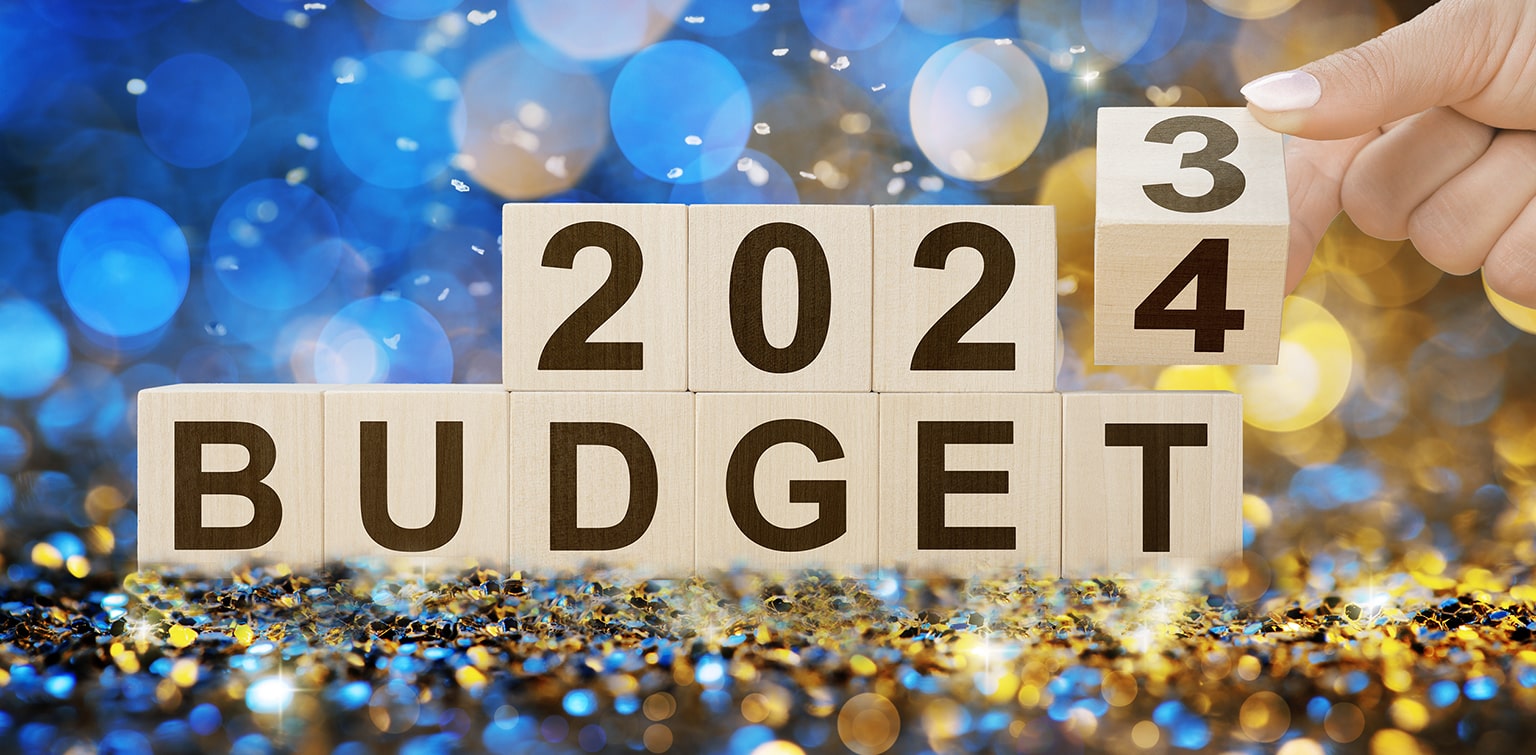 Woman flipping wooden cube from 2023 budget to 2024 budget on confetti background