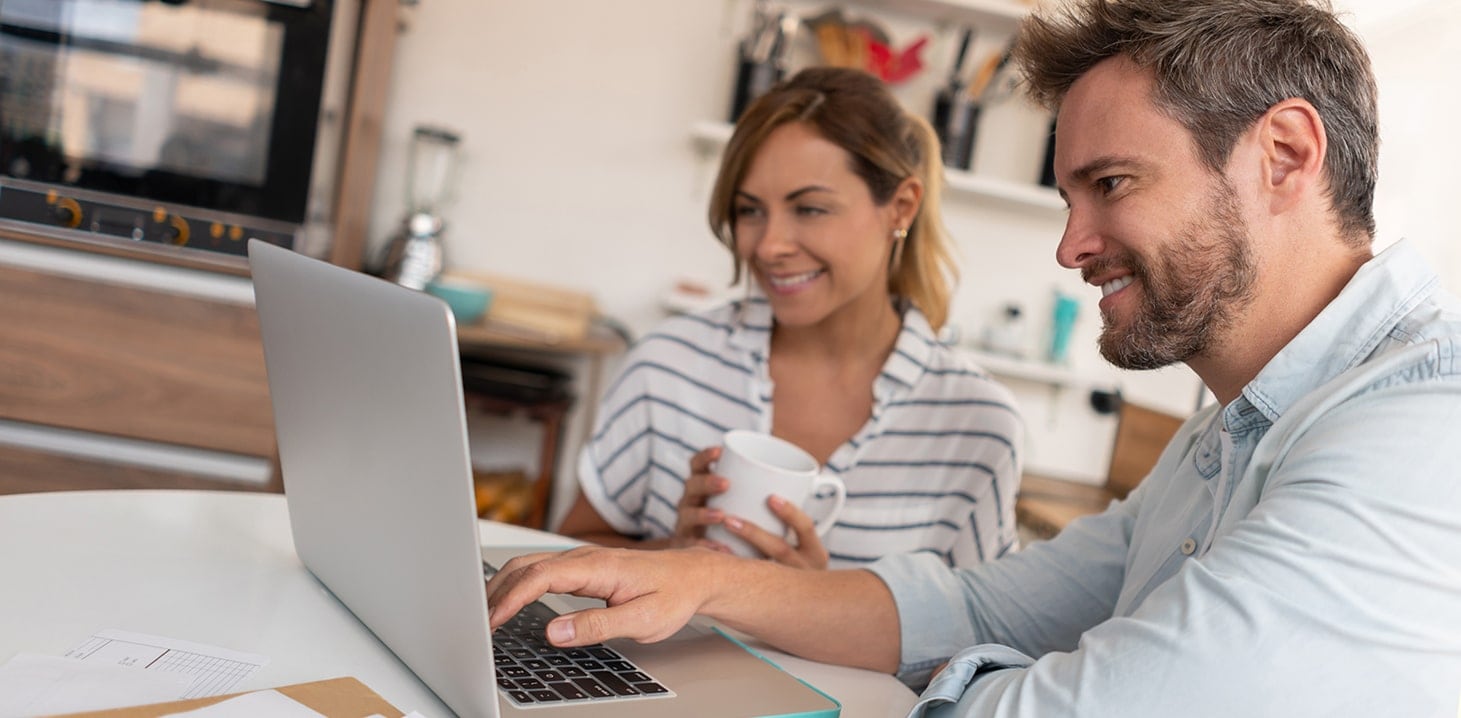 Smiling couple using laptop to pay bills