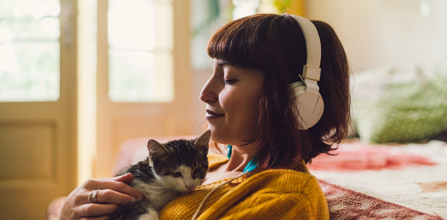 Woman listening to music and holding kitten