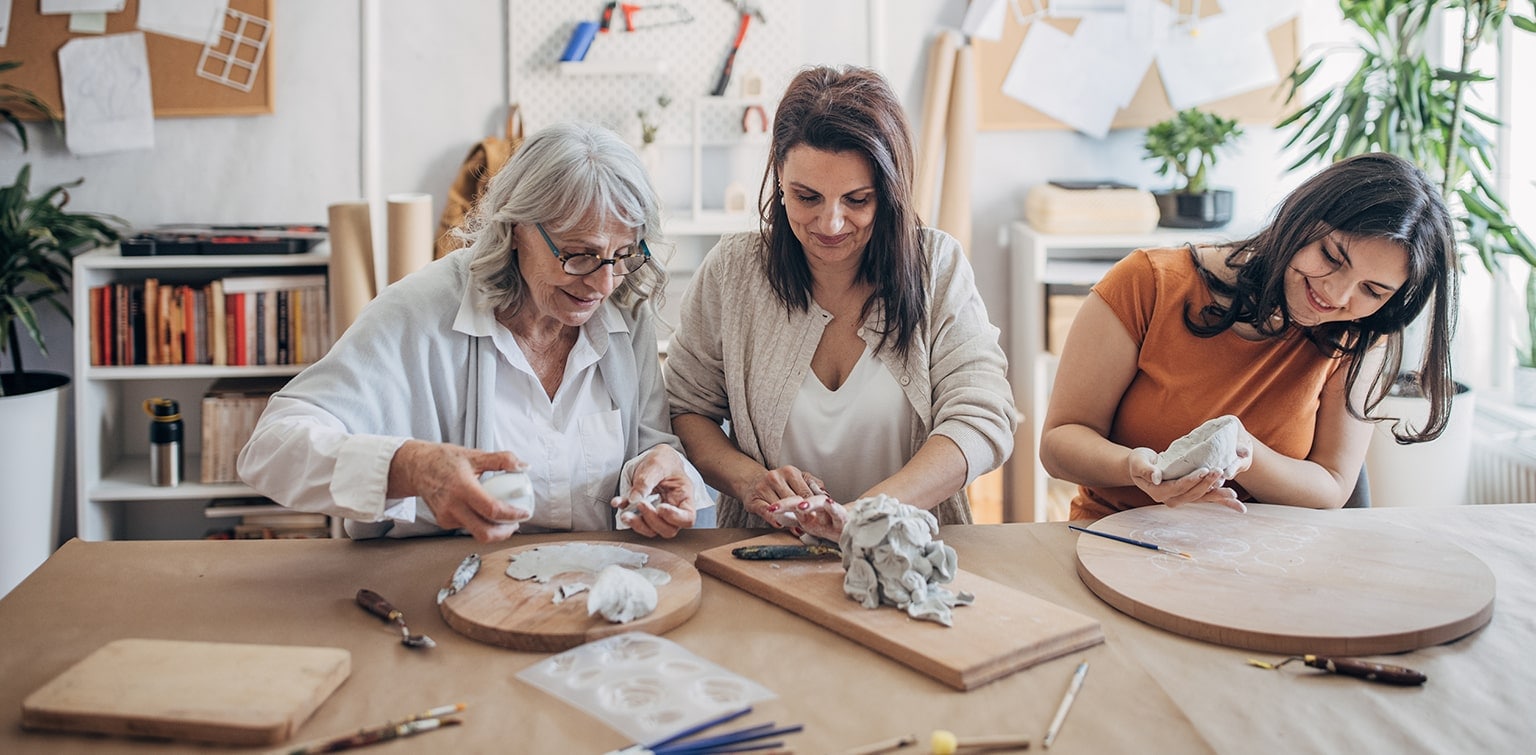 Woman working on pottery project with her mother and teenaged daughter