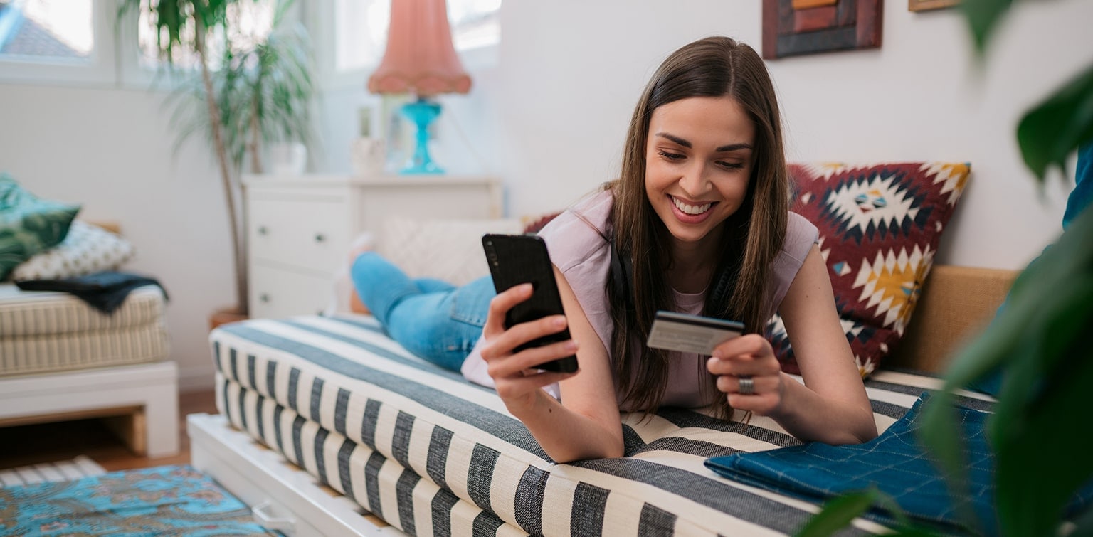 A woman on her phone holding a credit card