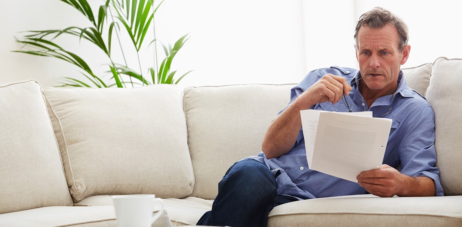 Middle-aged man reviewing documents on sofa